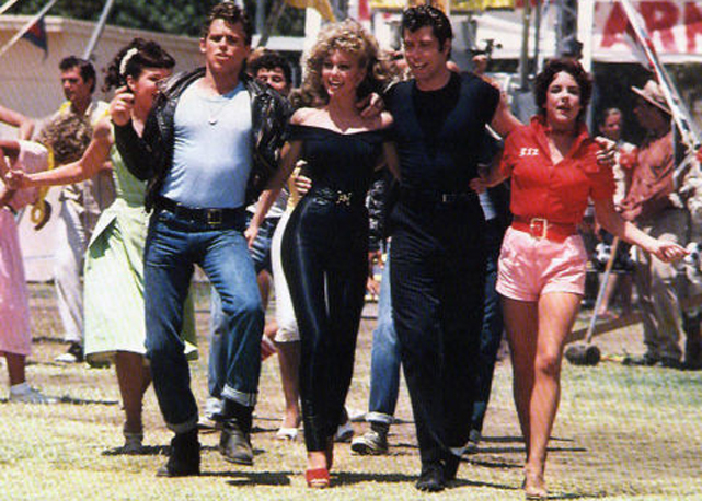 No centro, de preto, Olivia Newton-John como Sandy em Grease: Nos Tempos da Brilhantina - Foto: reprodução