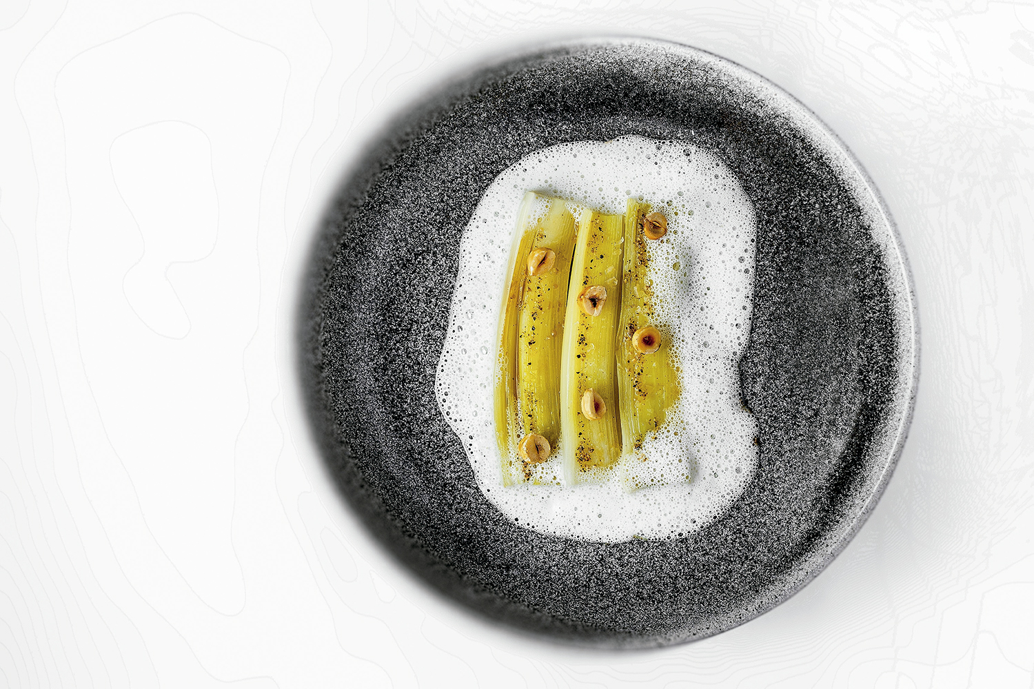 Alho-poró confitado e grelhado, servido com espuma de avelãs, do restaurante Evvai - Foto: Divulgação