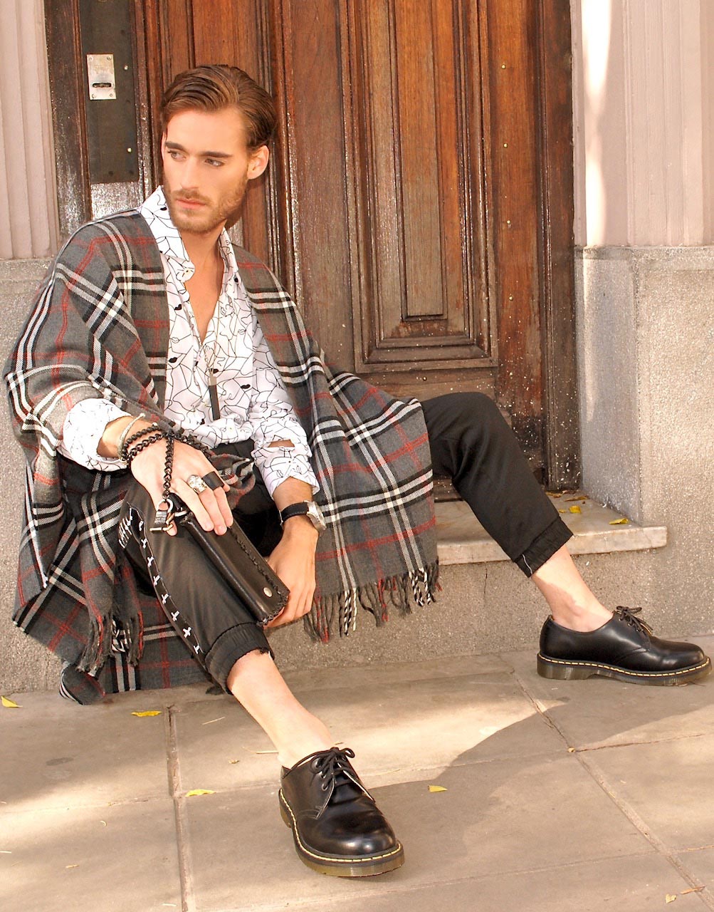 Poncho "escocês" com camisa geométrica: mistura de estampas e aposta em acessórios unissex como a bolsa-carteira. Modelo: Juan Roccabruna, com fotos de Labio Liebl, beleza de Nicolas Fernando Rodriguez e styling e produção executiva de Victor Drummond by Drummnod Comunicação