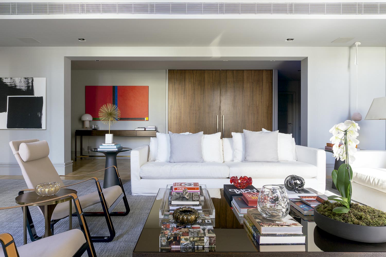 Obra de Eduardo Sued na sala de estar do duplex, que tem uma mesa de centro decorada com livros como destaque - Foto: Christian Maldonado, com styling Márcio e Flamínio Vicentini