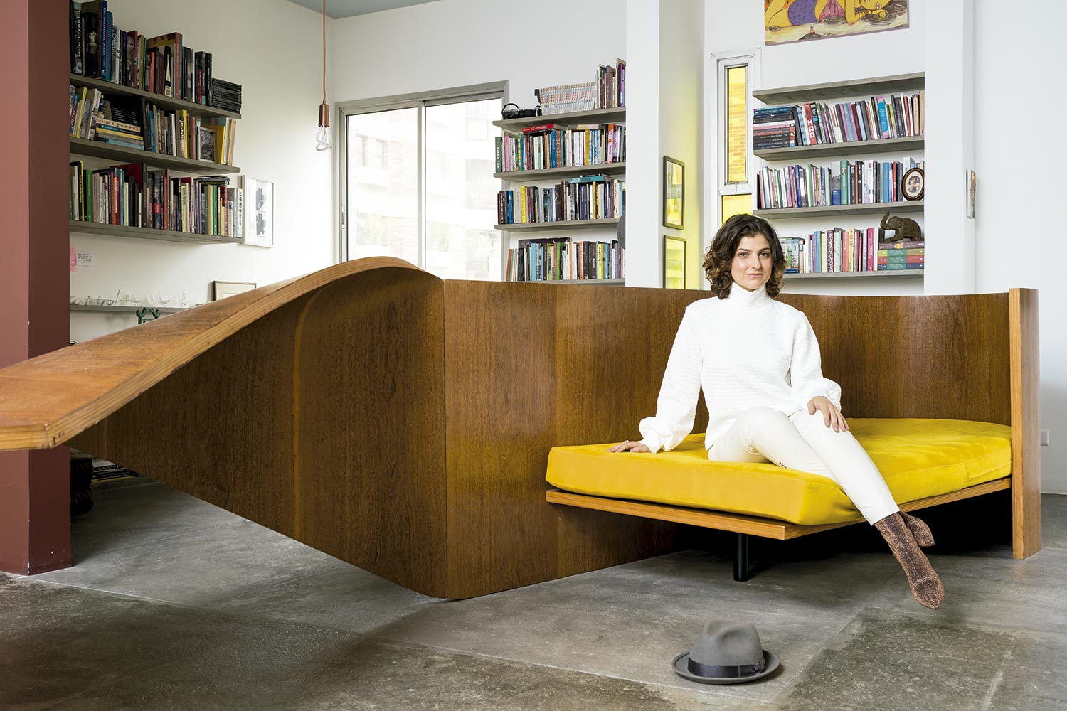 No  móvel "Fita", de Rodrigo Ohtake, ela veste blusa e calça Mayara Sansana e botas Paula Torres by Carol Bassi, com obra de OSGÊMEOS ao fundo - Foto: Christian Maldonado, com edição de moda Rodrigo Yaegashi