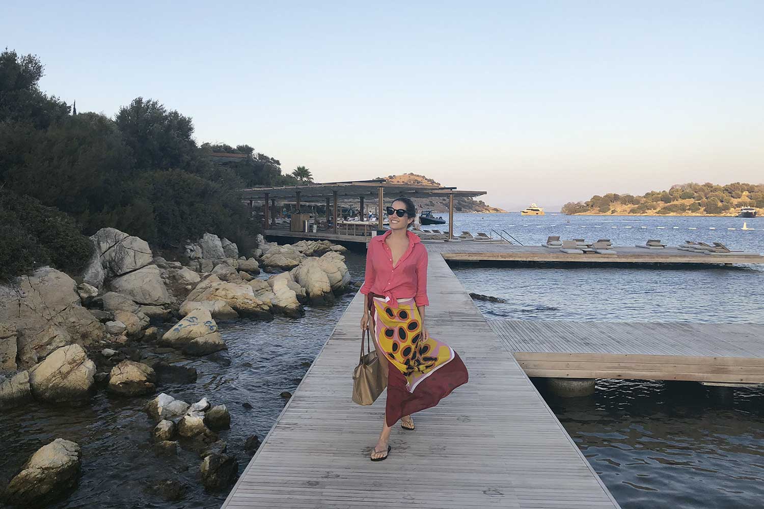 Marcela caminha em uma passarela de madeira sobre o mar no Maçakizi Hotel - Foto: Divulgação